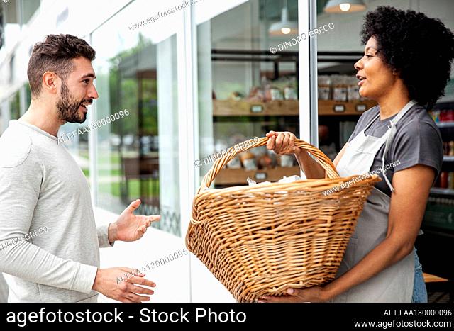 African American female bakery worker receiving basket from colleague