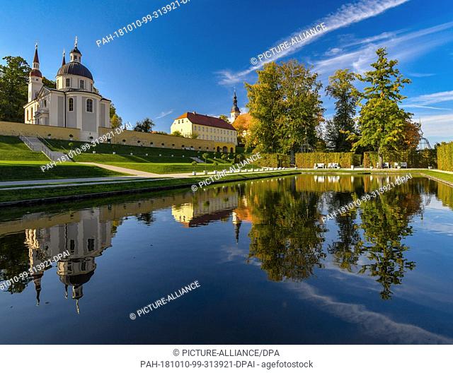 10 October 2018, Brandenburg, Neuzelle: The monastery complex in Neuzelle with the Catholic (M) and Protestant churches (l) is reflected in a pond in the...