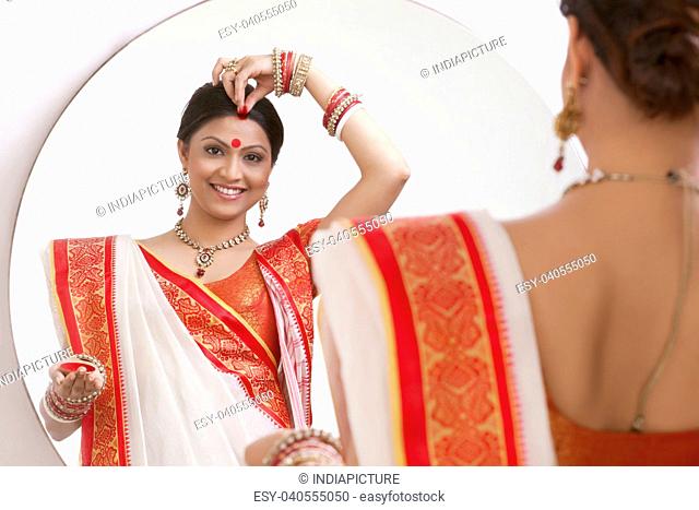 Portrait of Bengali woman putting sindoor on her forehead