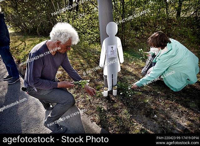 23 April 2022, Berlin: Roland Stimpel (l) and Annabelle Wolfsturm (r) lay flowers in front of the figure of a child on the edge of Landsberger Allee during a...