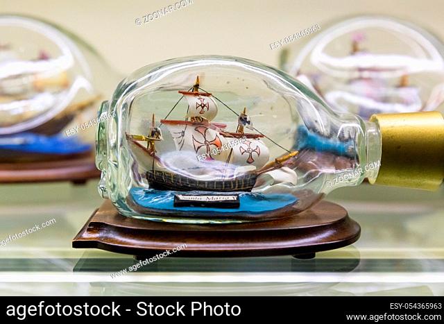 Istanbul, Turkey, 23 March 2019: Miniature tall ship with sails rigged in a clear glass bottle displayed on a small wooden stand over a white background