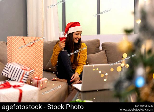 Happy Woman Making Video Call During Christmas Celebration holding wine glass