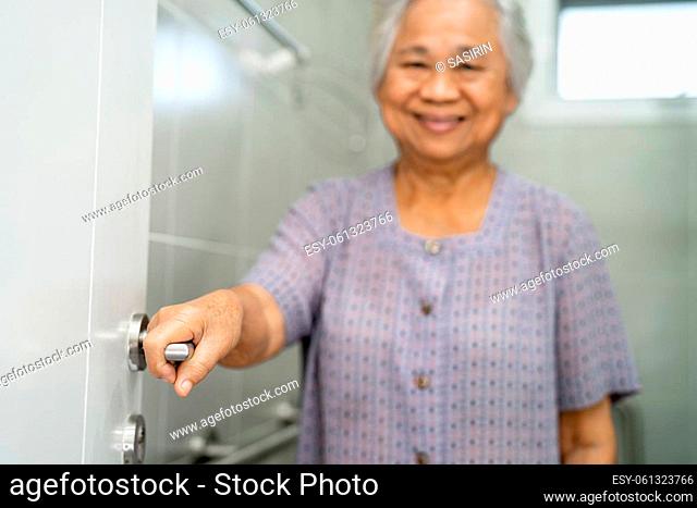 Asian senior elderly old lady woman patient open toilet bathroom by hand in nursing hospital ward, healthy strong medical concept