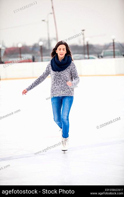 Young woman is skating on the rink, winter enjoing