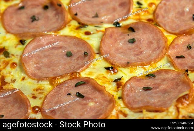 Homemade smoked tenderloin pizza and mozzarella cheese on blue checkered tablecloth background. Italian cuisine and cuisine. Homemade pizza dish