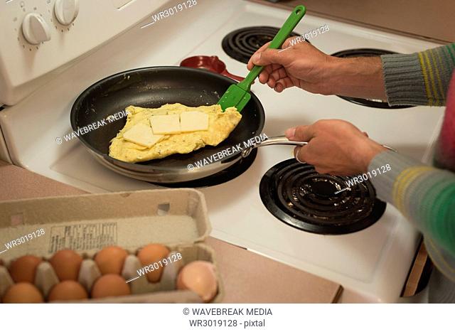 Man preparing scrambled eggs into frying pan