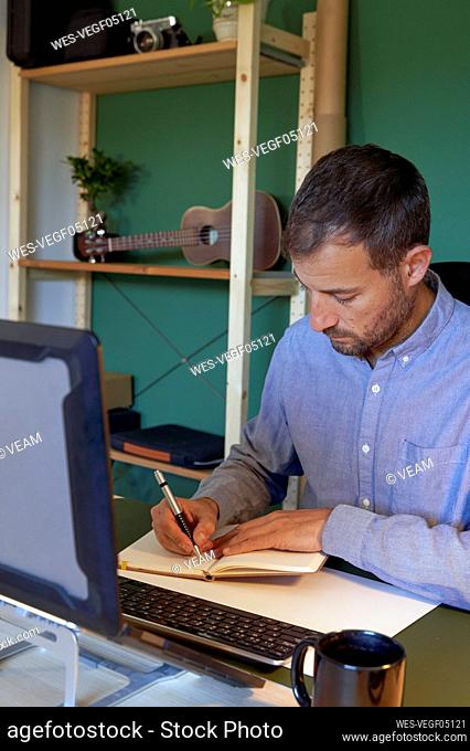 Freelancer writing on note pad in home office