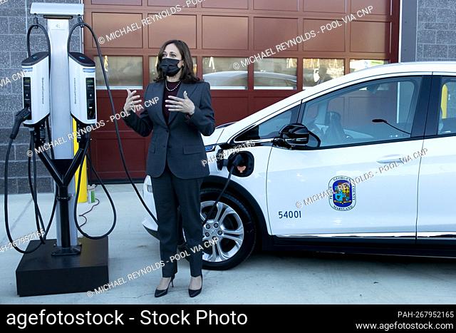 United States Vice President Kamala Harris (R) stands beside an electric vehicle while receiving a briefing about work to electrify the Prince George’s County...