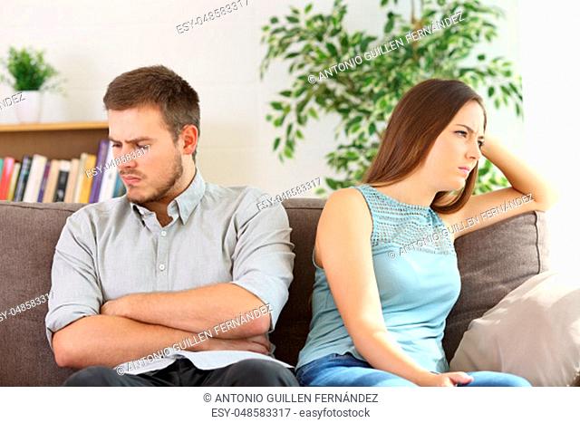 Angry couple ignoring each other after argument sitting on a sofa at home