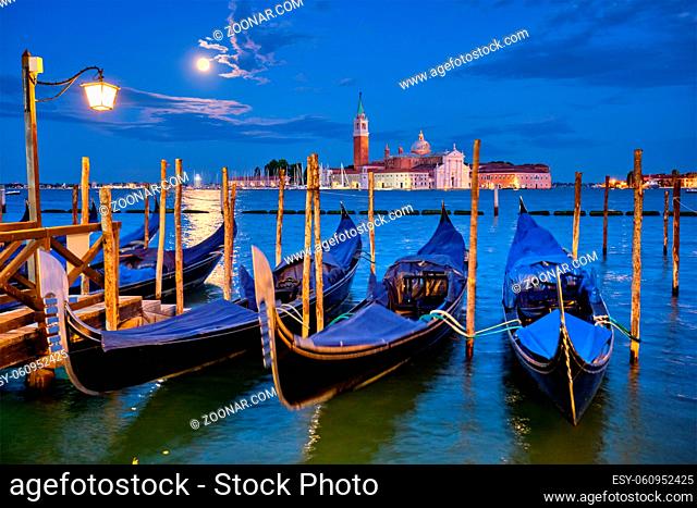 Romantic vacation Venice travel background - gondolas at Saint Mark (San Marco) square and Basilica San Giorgio Maggiore Church seen across Venice lagoon with...