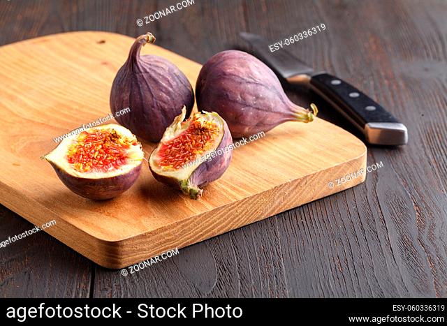 Fresh figs. Whole figs and sliced in half figs on wooden cutting board