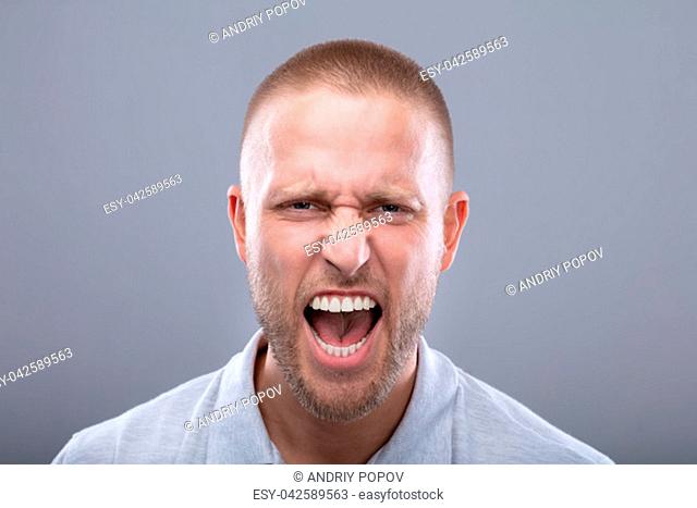Portrait Of A Shouting Young Man On Grey Background