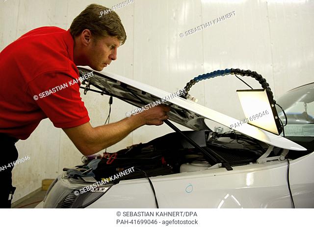 Car engineer Gvido Stalidzans removes a dent in a car that was caused by a hailstorm in Peine, Germany, 13 August 2013. Dent doctors go wherever storms have...