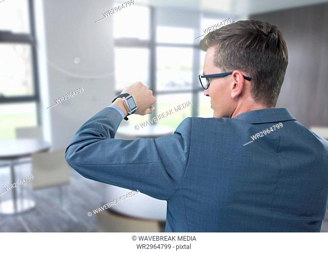 Businessman holding arm with watch to eyes in office