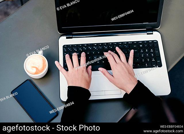 Businesswoman using laptop at cafe table