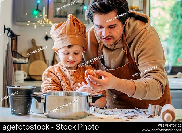 Smiling son cooking with father holding egg at table in kitchen