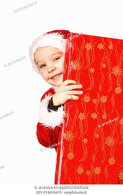 Smiling 5 year old boy wearing Santa Claus costume, Christmas gifts, white background