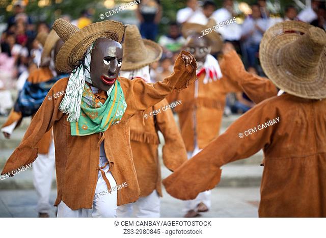 Dancers carrying masks during a performance at a traditional festival in the city center, Oaxaca, Mexico, North America