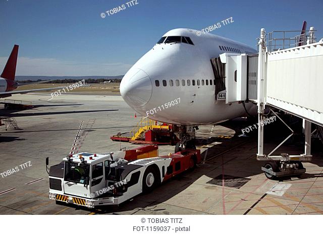 Jumbo jet attached to boarding bridge with tug in front