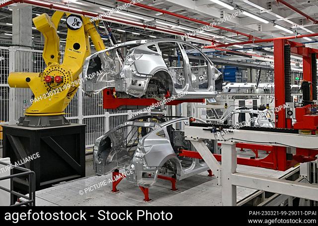 20 March 2023, Brandenburg, Grünheide: The largest robot named King Kong at the Tesla Gigafactory Berlin Brandenburg plant lifts the body of the Model Y...