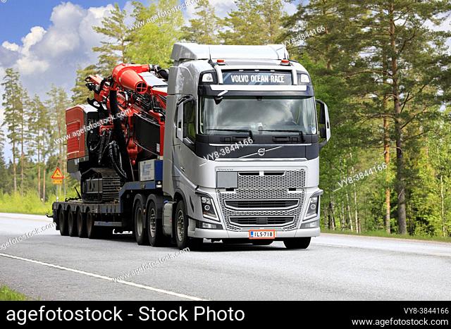 Silver Volvo FH16 truck transports Sandvik Pantera DP1100i top hammer drill rig on low bed trailer on road 25. Raasepori, Finland. May 27, 2021