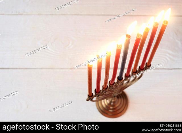 Hanukkah menorah with burning candles on the white wooden table