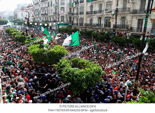 05 July 2019, Algeria, Algiers: Algerians hold national flags and placrds as they take part in a march calling for the departure of the Algerian regime...