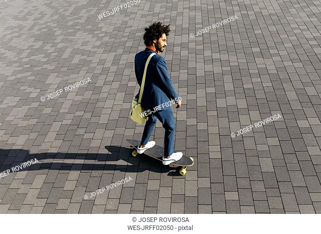 Young businessman riding skateboard on a square