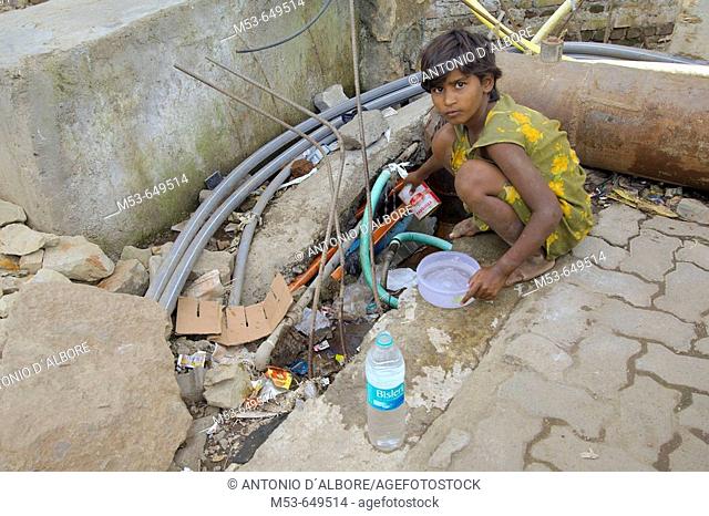 an homeless girl steal water from the public water pipe. sakinaka district. mumbay. maharashtra. india. asia