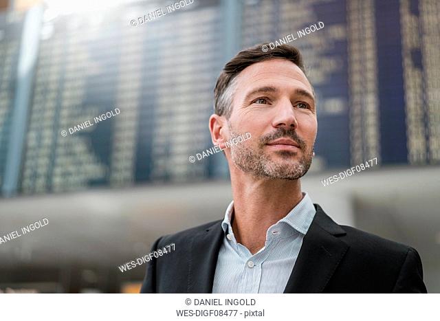 Portrait of businessman at arrival departure board at the airport