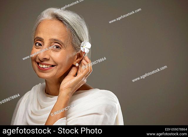 Portrait of old beautiful woman touching the flower in her hair