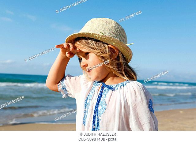 Cute girl on beach shielding her eyes, Castellammare del Golfo, Sicily, Italy