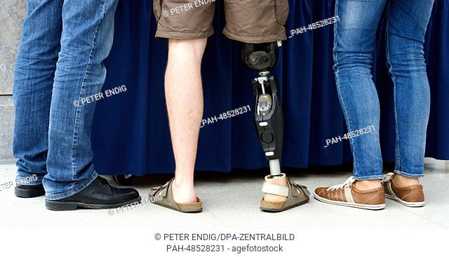 A man with a leg prosthesis (C) by company Otto Bock (Lower Saxony) stands between two other people at the trade show OT World 2014 in Leipzig, Germany