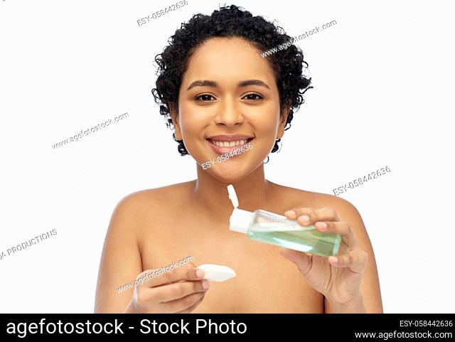 happy african woman with cotton pad an lotion