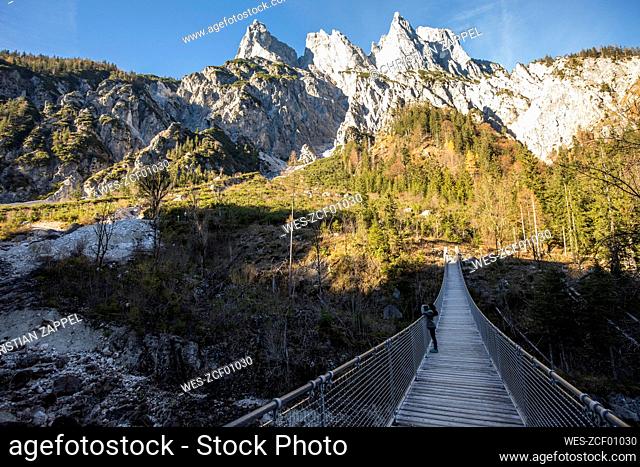 Germany, Bavaria, Female hiker taking photos from suspension bridge in Berchtesgaden National Park