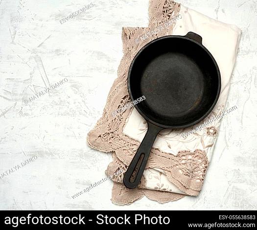 empty black round frying pan with handle, white table, top view