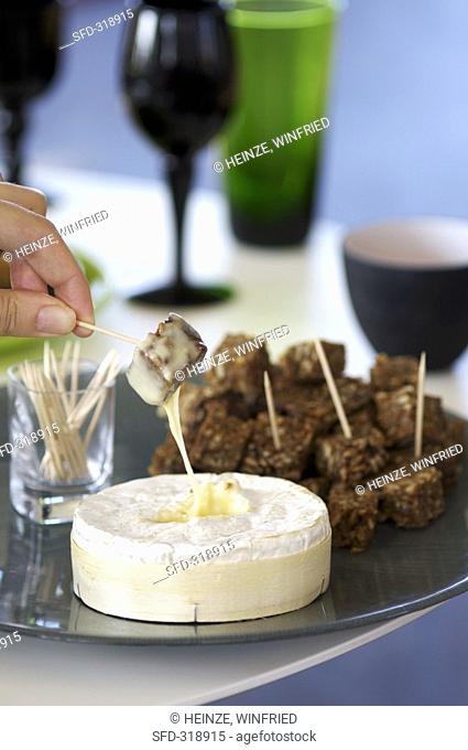 Dipping a bread cube in melted Camembert