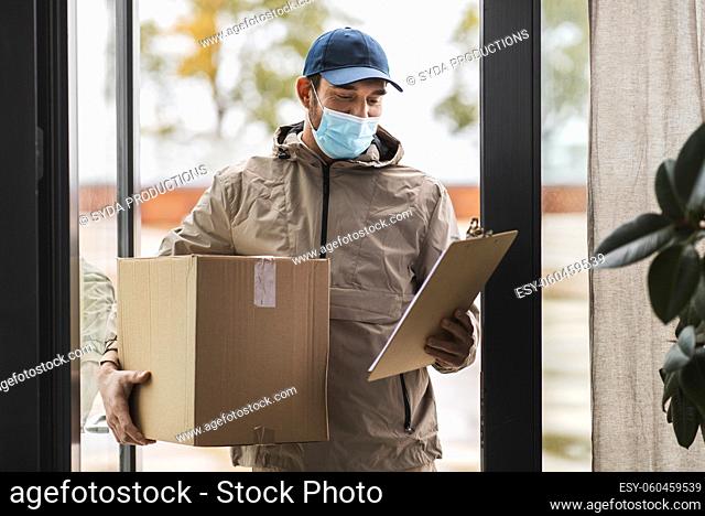 delivery man in face mask holding parcel box