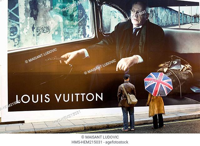 United Kingdom, London, Mayfair, pedestrians with a Union Jack umbrella looking at an advertisement for Louis Vuitton with Mikhail Gorbatchev