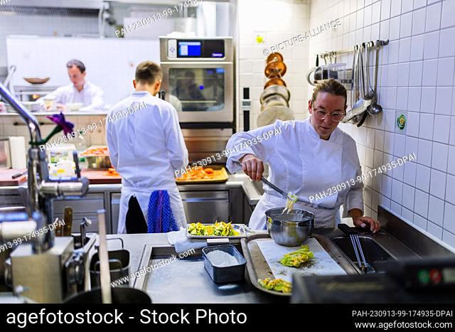 PRODUCTION - 31 August 2023, Baden-Württemberg, Sulzburg: A cook (l) and a female cook (r) stand in the kitchen of the two-star Hirschen restaurant and prepare...