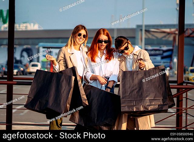 Young women with shopping bags on a bus stop posing for the camera