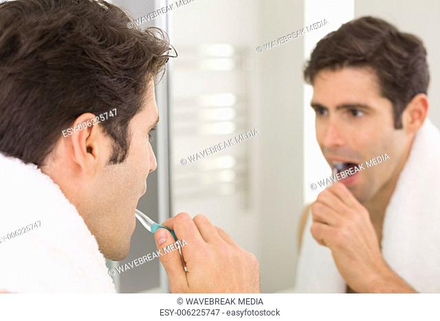 Man with reflection brushing teeth in the bathroom