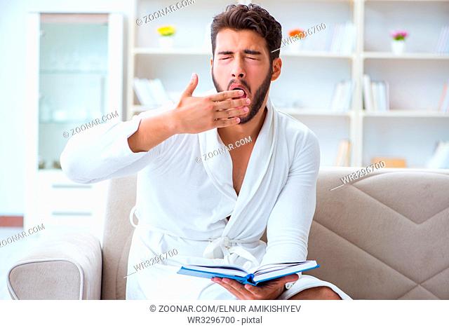 Young man student businessman reading a book studying working at home