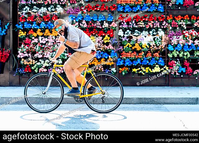 Portrait of bearded man on fixie bike sticking out tongue and showing Rock And Roll Sign