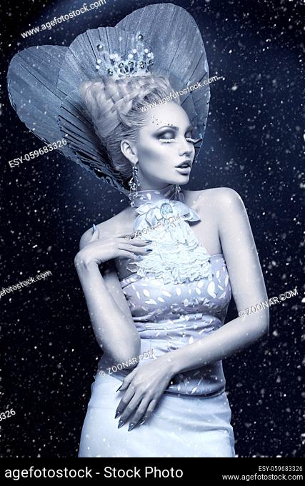 Portrait of beautiful young woman dressed as winter queen. Creative makeup. Over dark background. Copy space