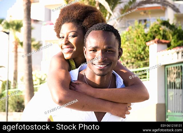 Couple of black young man and woman enjoy and smile together in piggyback carrying friends activity - concept of happy people have fun in friendship and...