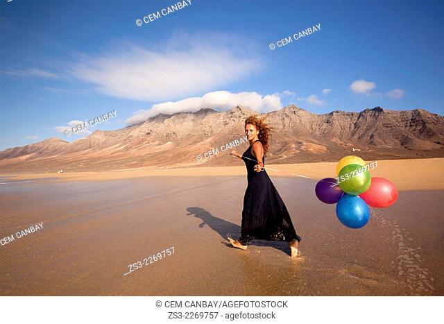 Woman with colorful balloons at Playa de Cofete beach, Fuerteventura, Canary Islands, Spain, Europe