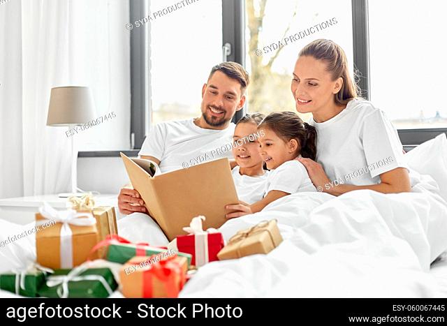 happy family reading book in bed on christmas
