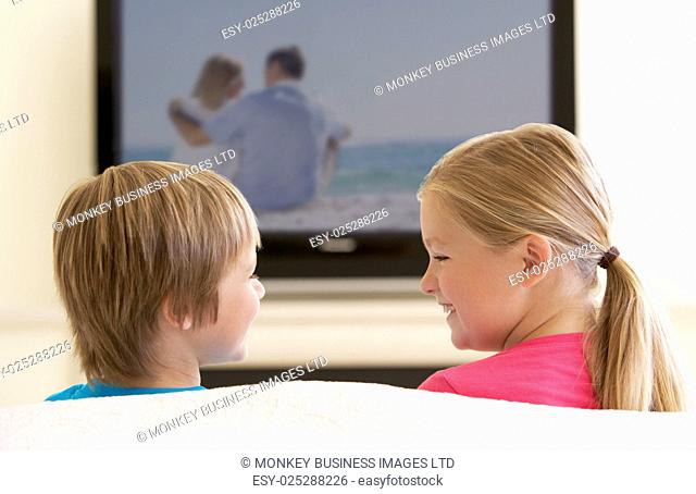 Two Children Watching Widescreen TV At Home