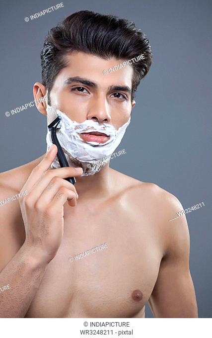 Portrait of young man shaving